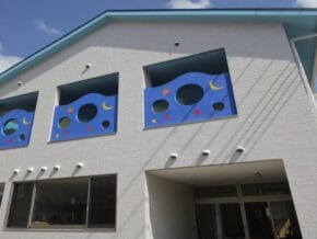 White brick building with three blue square windows featuring moons and stars above the entrance.