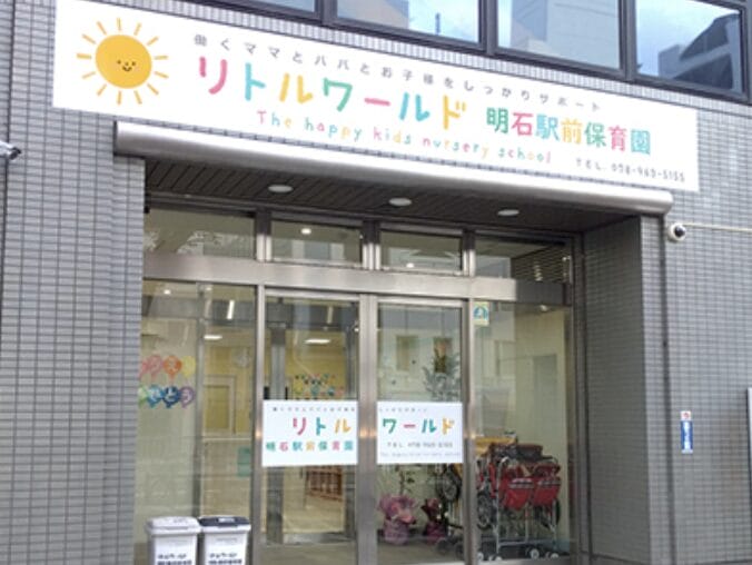 Front entrance of a daycare with a colorful sign reading 'Little World' and 'The happy kids nursery school' beneath, sun logo on the left.