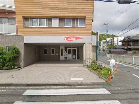 Ground-level storefront with a covered entry and a small parking area; a crosswalk is visible across the street in front.