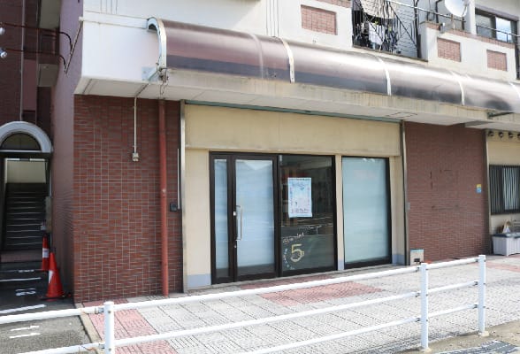 Closed storefront with glass doors and a poster in the window, on a brick building with a curved awning above.