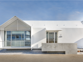 Modern white building with a gabled lattice façade and large glass front, set under a blue sky.