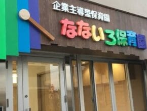 Colorful daycare center storefront with rainbow panels and Japanese signage above glass doors.